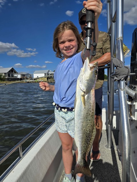 Young angler holding a speckled trout on a private 30A fishing charter