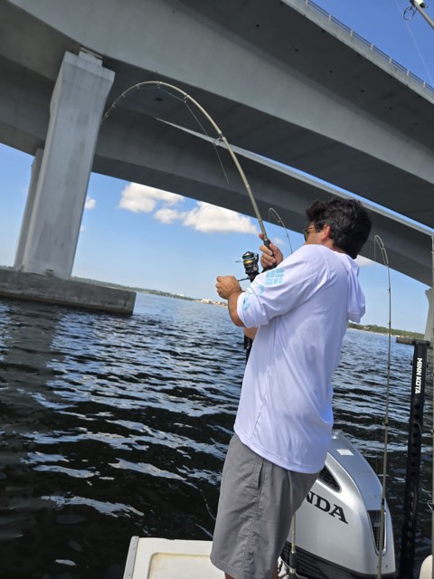 Angler fighting a fish beneath a bridge near 30A