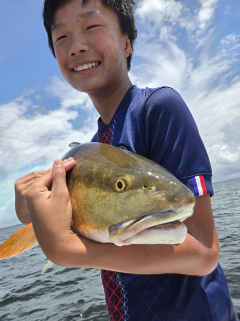 Guest holding an inshore catch during a private charter