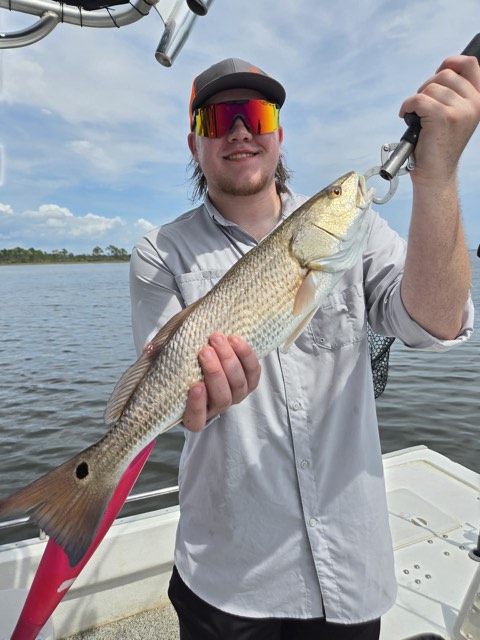 Angler holding a redfish during a 30A bay fishing trip