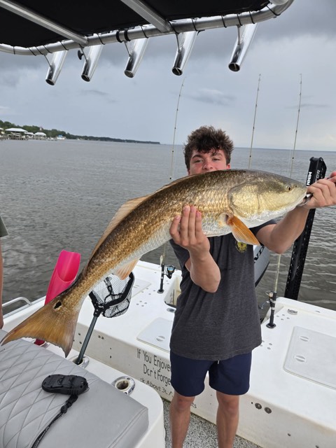 Young angler proudly holding a redfish near South Walton